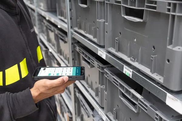 Warehouse worker using a handheld barcode scanner to identify storage bin inventory.